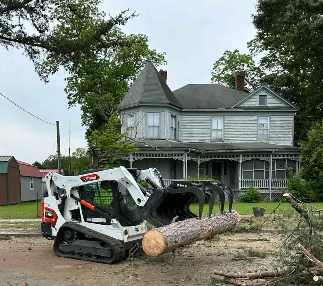 Crane lifting tree section over brick residential home