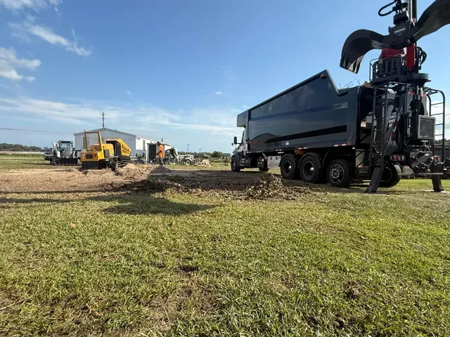 Grapple claw grabbing tree sections at job site