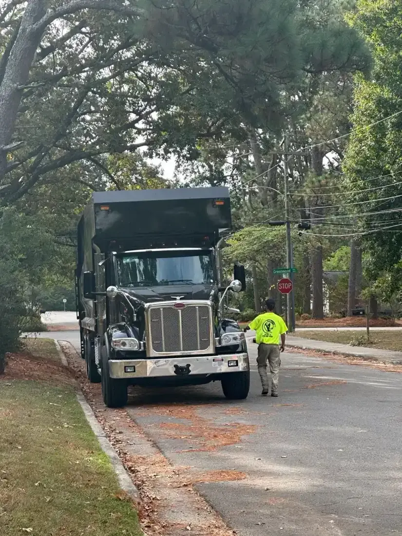 DC Tree Cutting crew in hi-vis gear with Peterbilt grapple truck on a commercial property