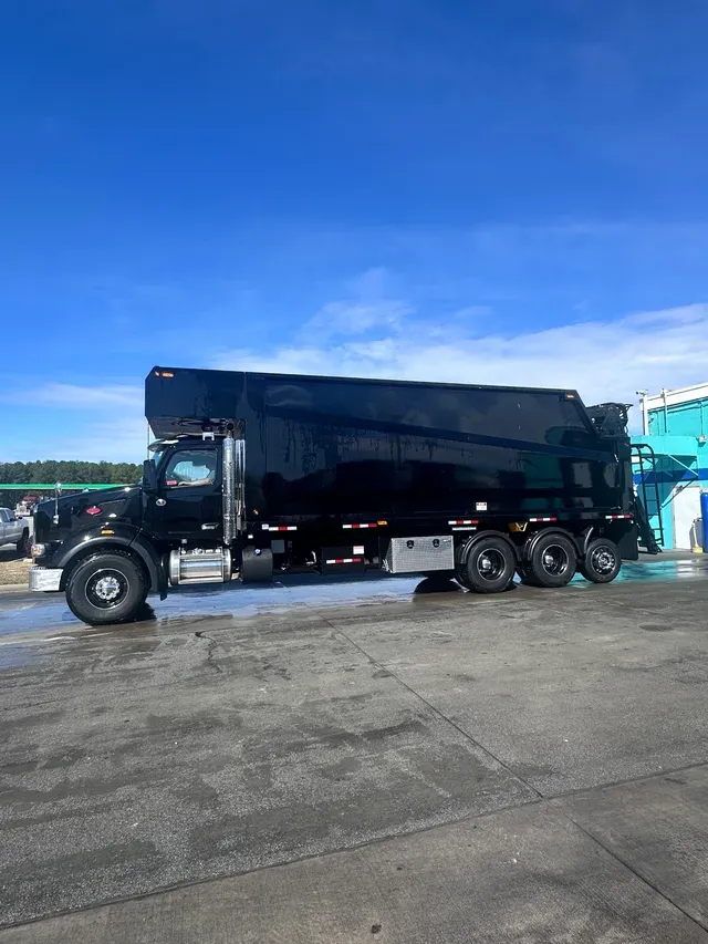 Rear view of grapple truck at a cleared site under blue sky