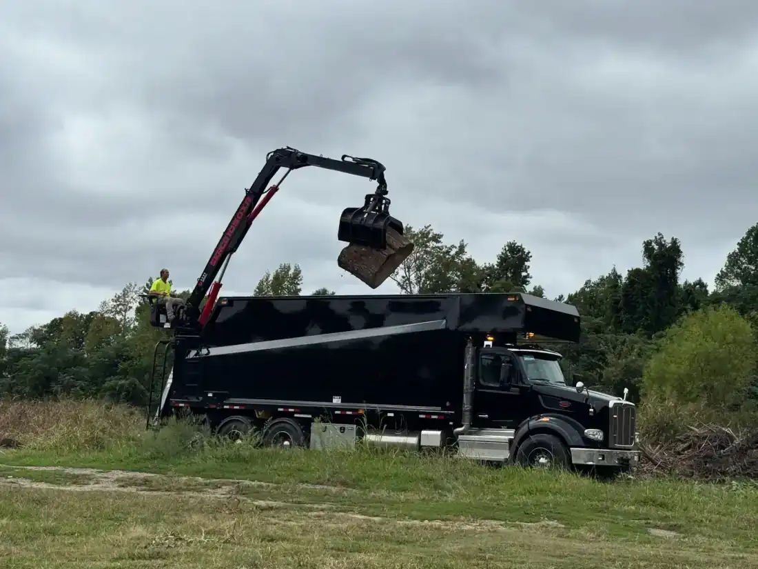 Peterbilt grapple truck loading tree debris with hydraulic claw