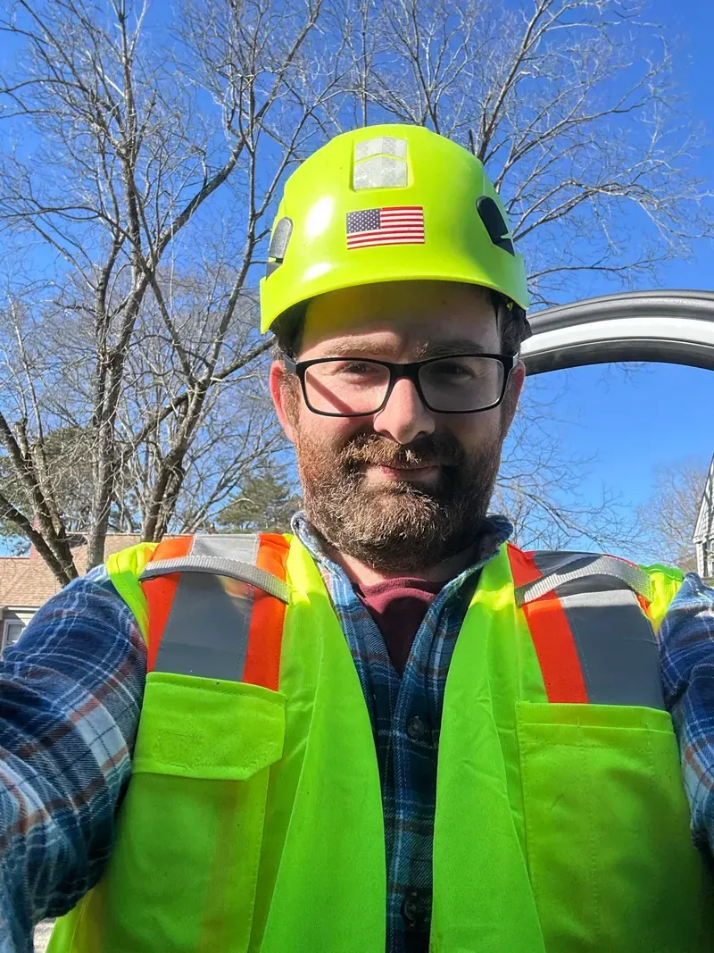 Anthony Caracappa of DC Tree Cutting and Land Service on a job site wearing a hard hat and high-visibility safety vest
