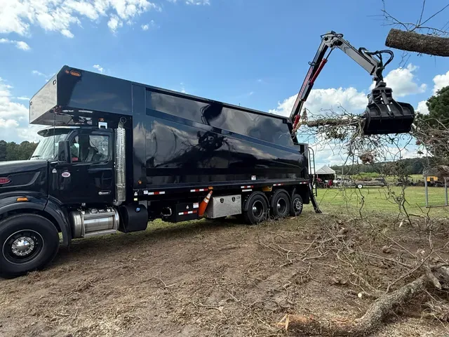 Grapple truck loading tree debris at job site