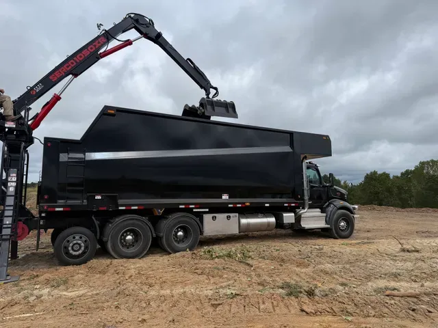 Grapple truck with crane extended loading debris